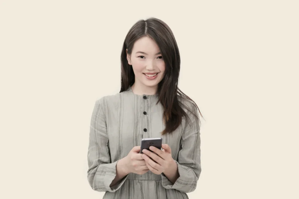 Mulher sorrindo enquanto usa o celular